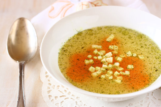 chicken soup with carrots over white wooden textured background