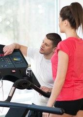 Obraz premium Trainer explains to a young woman how to use treadmill 
