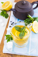 Cup of tea with mint and lemon on a wooden surface