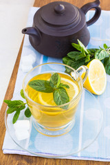 Cup of tea with mint and lemon on a wooden surface