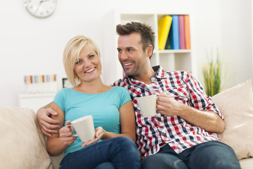 Beautiful couple relaxing on sofa with cup of coffee