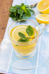 Cup of tea with mint and lemon on a wooden surface