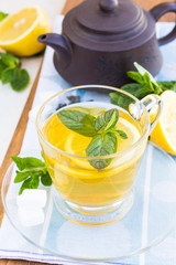 Cup of tea with mint and lemon on a wooden surface