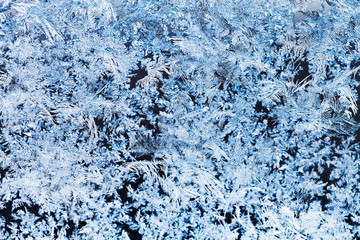 snowflakes and frost pattern on glass close up
