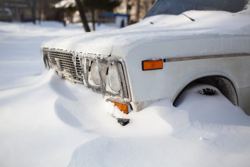 White old car covered with snow