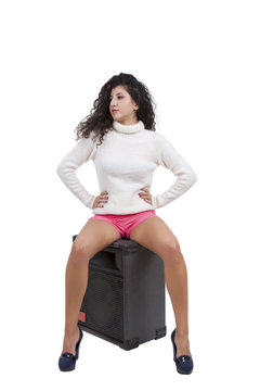 Young female fashion model sitting on a speaker