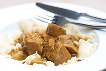 pork pieces on cumin with pasta