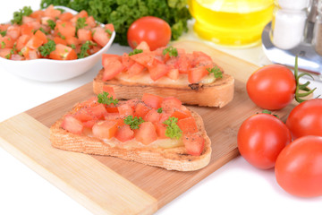 Delicious bruschetta with tomatoes on cutting board close-up