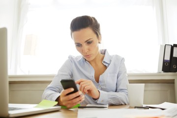 Young businesswoman sending a text message