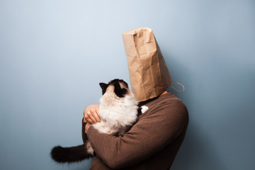 Young man with bag over head holding his cat