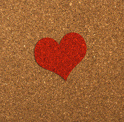 Red heart on a cork board.