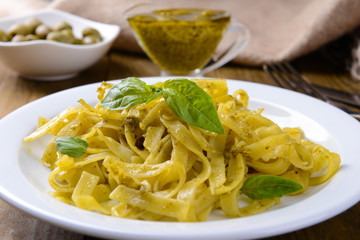 Delicious pasta with pesto on plate on table close-up