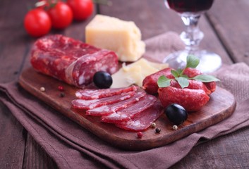 board with snacks: cheese, sausage, tomatoes