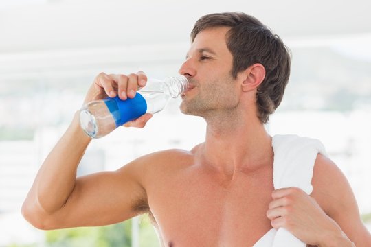 Shirtless man with towel drinking water