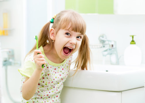 kid girl brushing teeth in bathroom