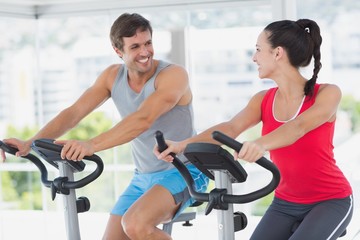 Fototapeta premium Smiling couple working out at spinning class