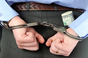 Man's hands in handcuffs with money in his pocket