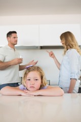 Fototapeta premium Sad girl leaning on table while parents conflicting