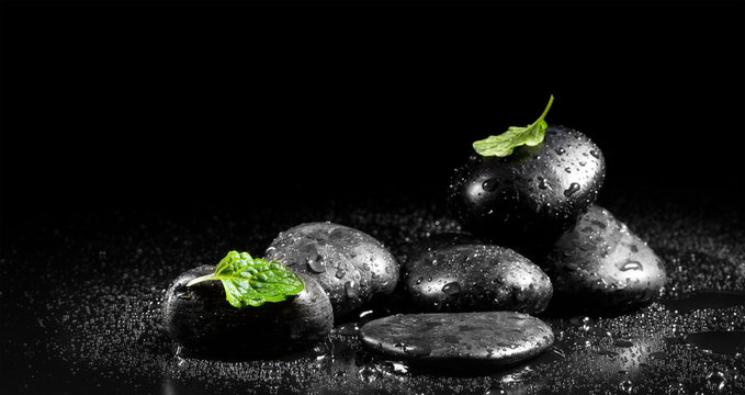 Zen stones with mint leaves on a black background