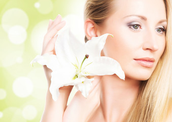 A healthy girl with a fresh lily flower on a light background