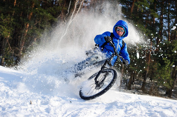 Obraz premium Cyclist riding on a mountain bike in the snow winter forest