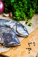 Fresh sea bass on board before preparation on rustic wooden back