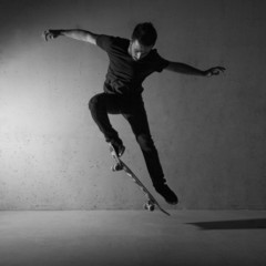 Skateboarder doing a skateboard trick - ollie - against concrete