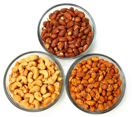 Three glass bowls filled with cashews, salted roasted almonds an