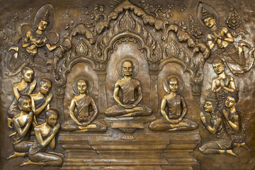 Buddha life scenes on carved metal at the temple in Thailand.