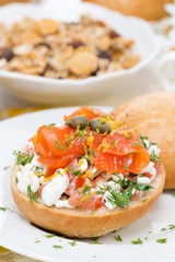 bun with cottage cheese, herbs, tomato and salmon, close-up