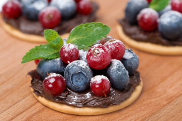 cake with chocolate cream and fresh berries on wooden background