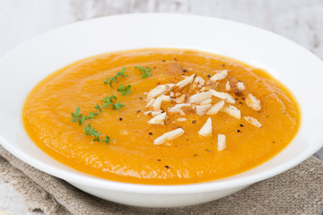 carrot soup with almonds and watercress on wooden table