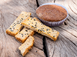 Freshly toasted salt and sesame bread and banana cupcake on wood