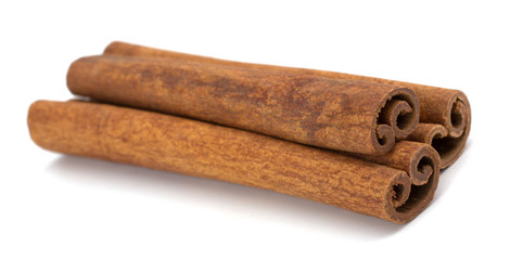 cinnamon sticks stacked on white background 