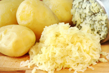 Mashed potatoeswith potato ricer at the background