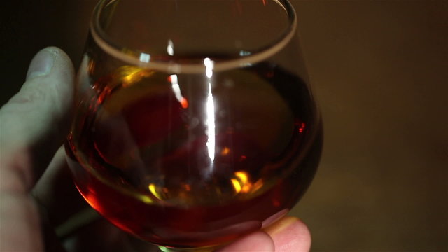 Man's hand with a glass of cognac, brandy close up