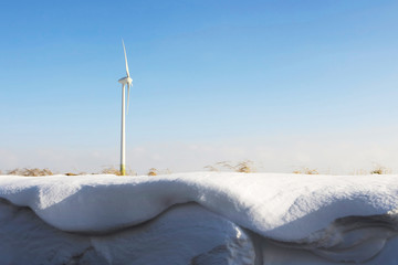 Windmill with snowdrifts and grass