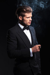 side of a fashion man in tuxedo smoking a cigar
