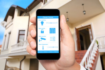 male hand hold a phone with system clever house on the backgroun