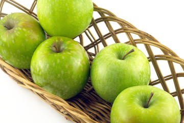 Ripe green apples in long brown wicker basket isolated closeup