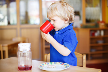 Little baby boy at nursery eating breakfast