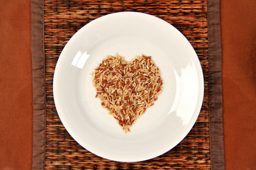 Brown rice grains in the form of heart on bowl