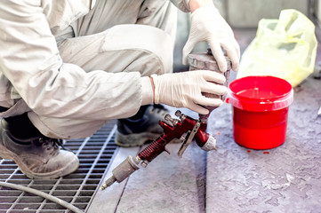 Industrial worker preparing red paint for spraying a car