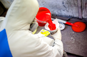 Auto mechanic mixing and pouring red paint for spraying
