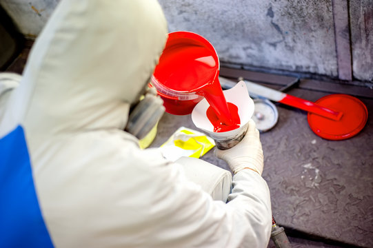 Auto mechanic mixing and pouring red paint for spraying