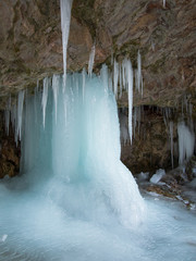 Large ice pillar stands in a cave near the icicles