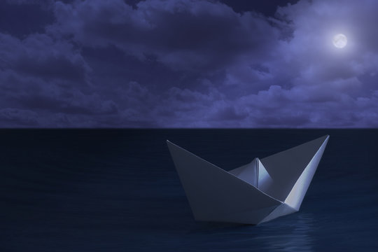 Paper boat floating in the sea at night - Powered by Adobe