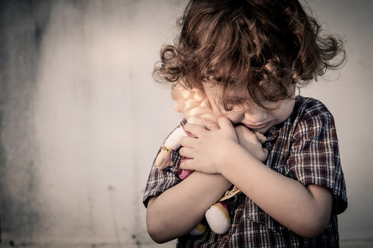 sad little boy hugging a doll