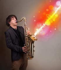 Fototapeta na wymiar Young man playing on saxophone with colorful sound waves