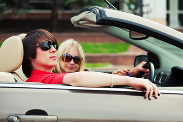 Happy young couple driving convertible car